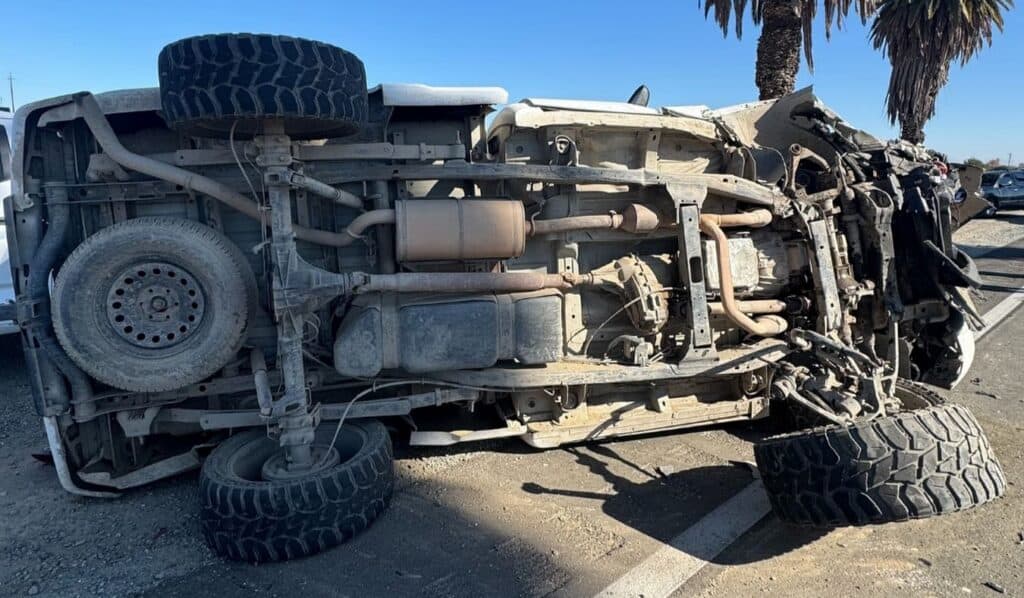 Upside-down truck accident on the road with visible damage.