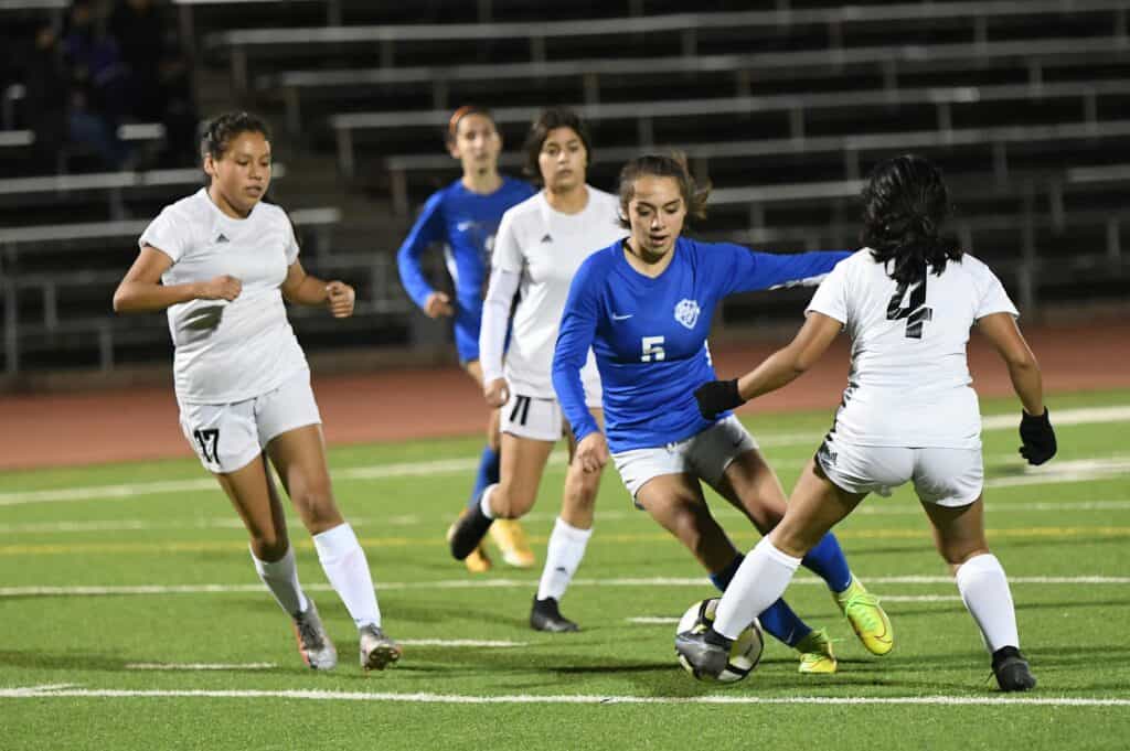 Young girls playing soccer on a field during a youth match.