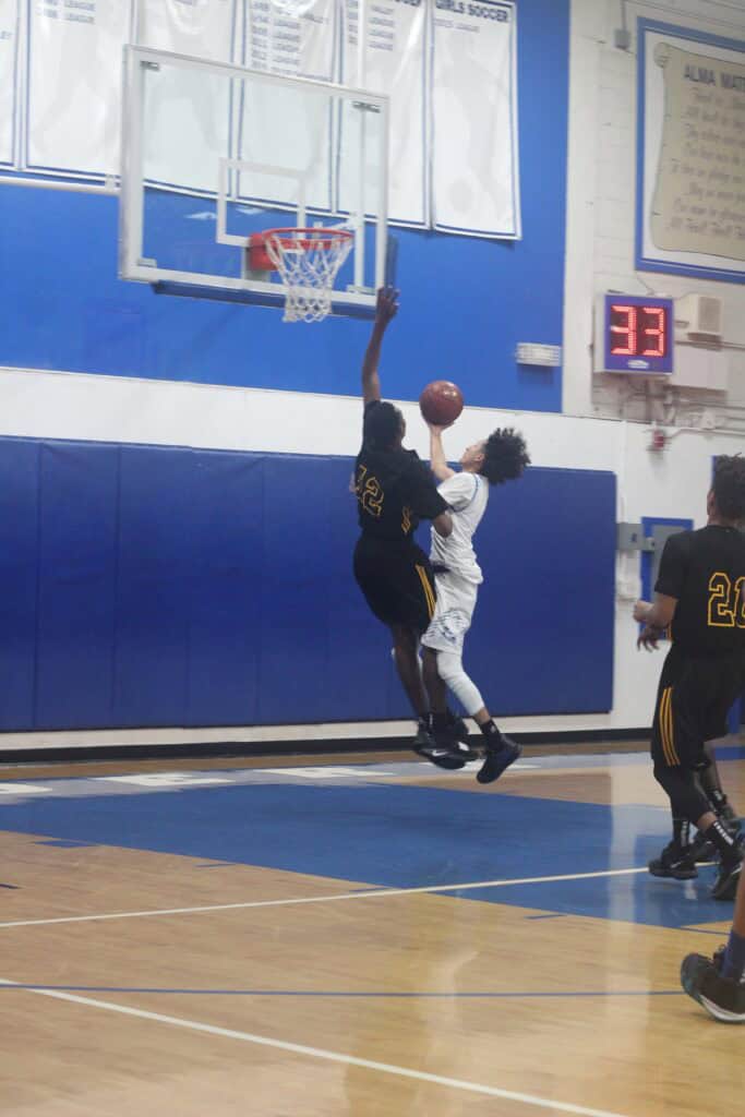 Youth basketball game with player attempting a shot near the hoop.