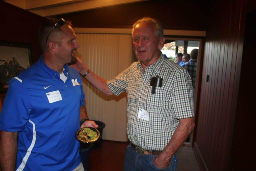 Two men talking at a Madera Tribune community event, smiling and engaging.