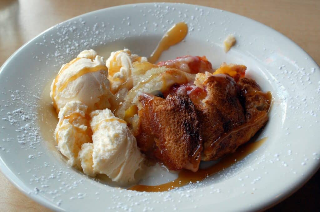 Delicious apple pie served with vanilla ice cream on a white plate.