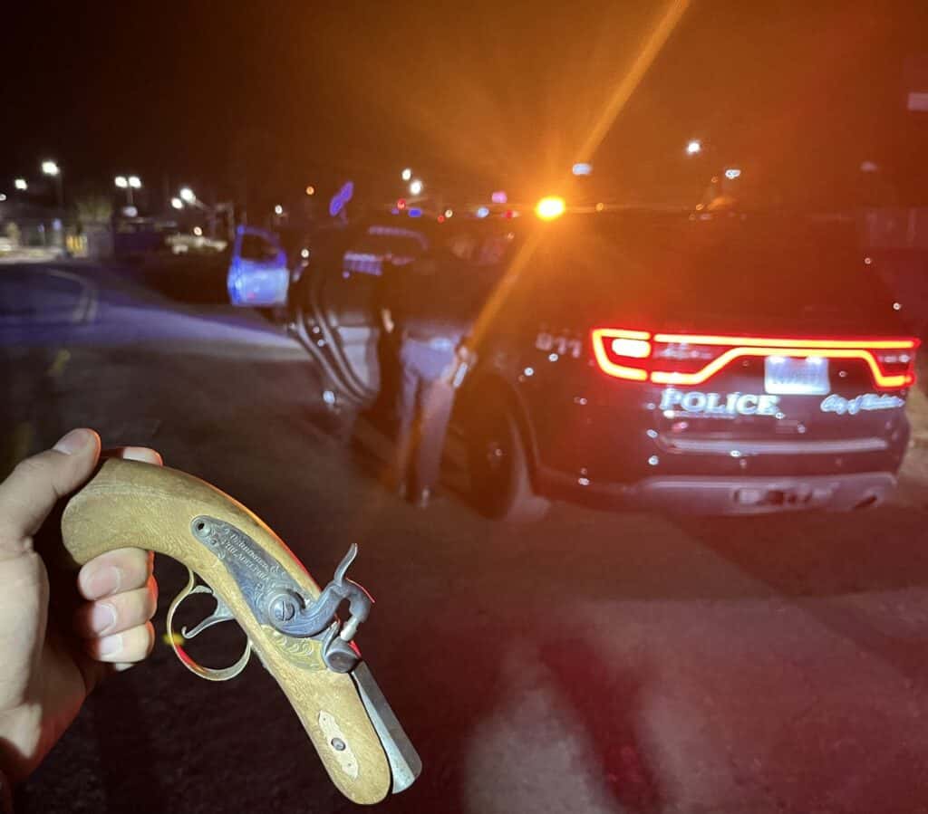 Nighttime police scene with officers and a toy gun in the foreground.