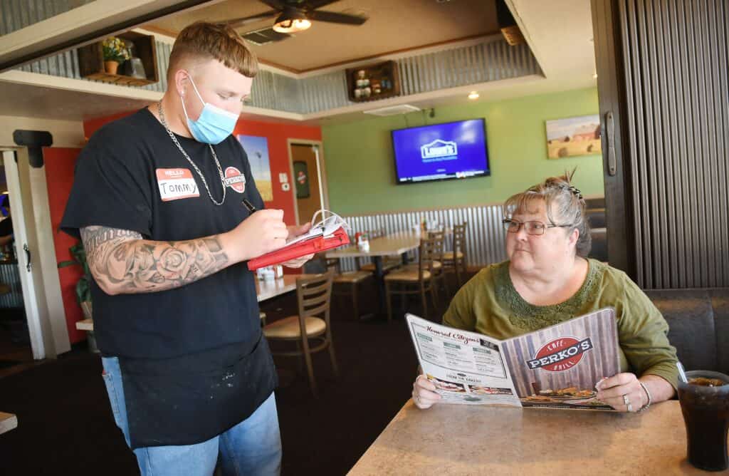 Young waiter taking order from customer with newspaper.