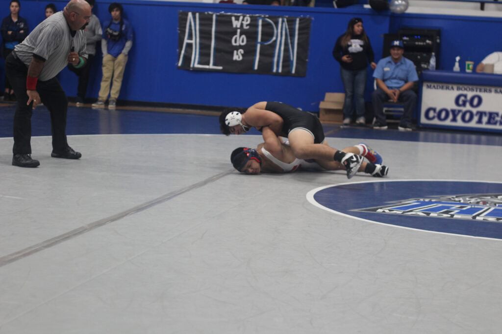 Madera wrestler pins opponent during high school match at Madera gym.