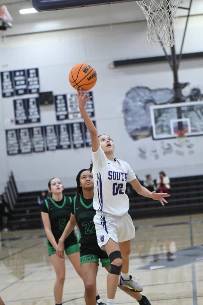 Young female basketball player shooting a layup during a game.