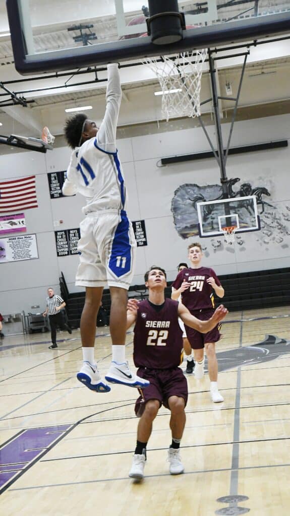Player in white jumps for a dunk during a basketball game.