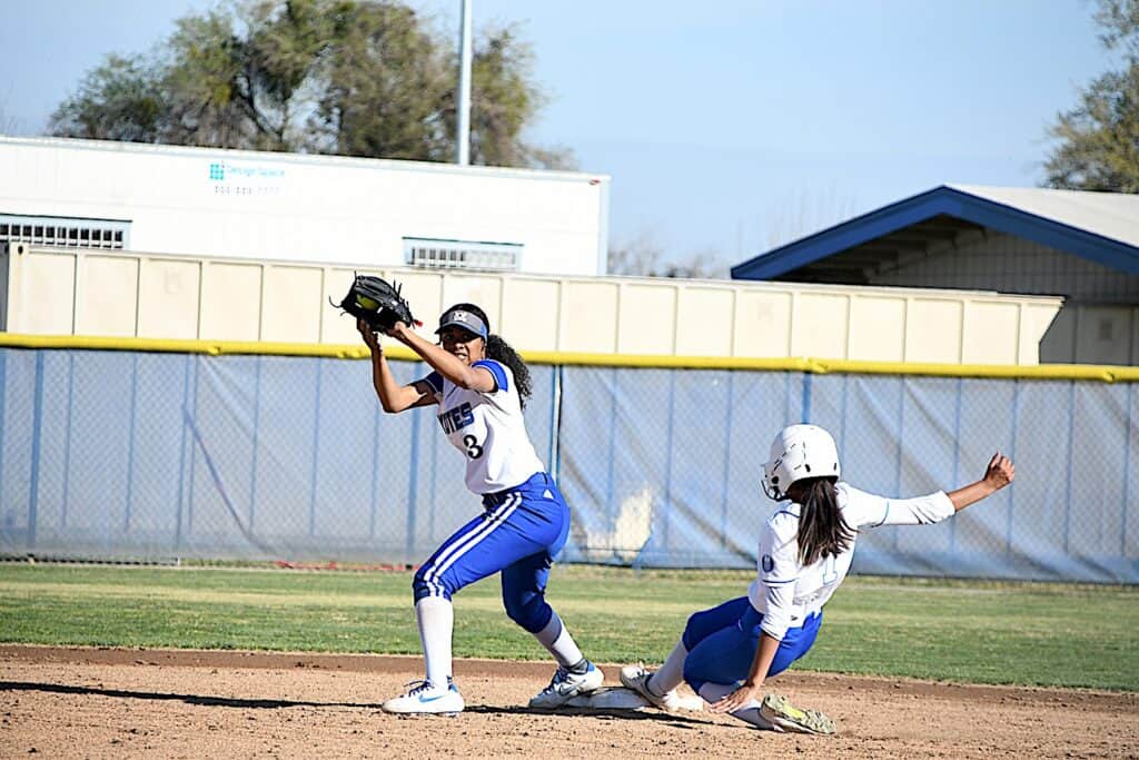 Female softball player catching a ball during game.