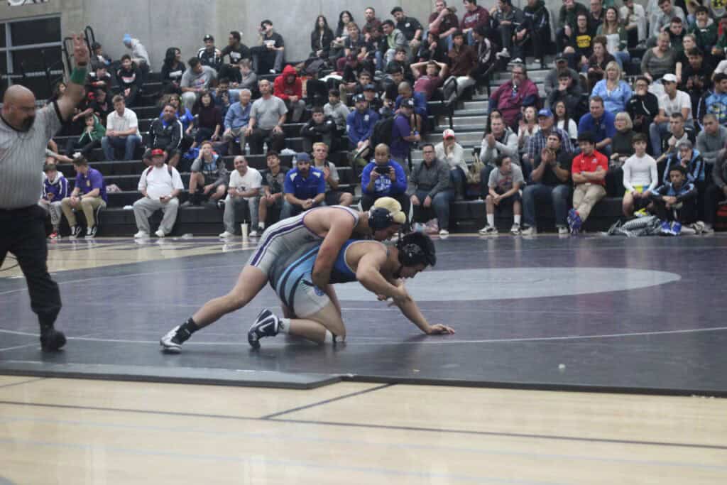Madera High School wrestlers competing in a match with spectators watching.