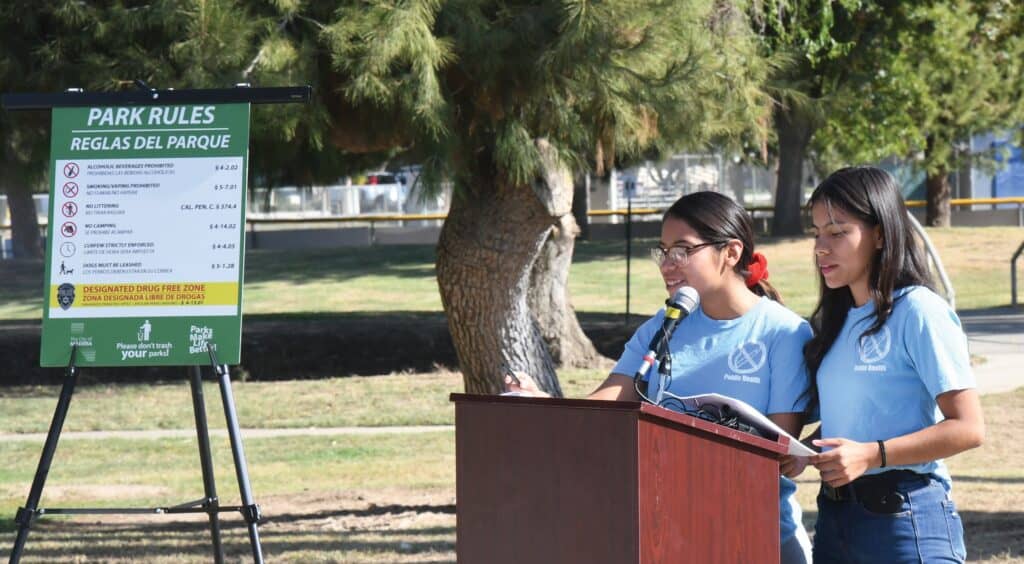Two young women speaking at a park rules announcement in Madera.