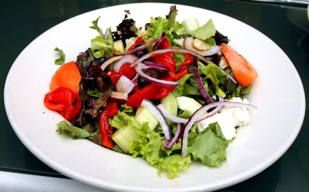 Fresh garden salad with mixed greens, tomatoes, cucumbers, and red onions.