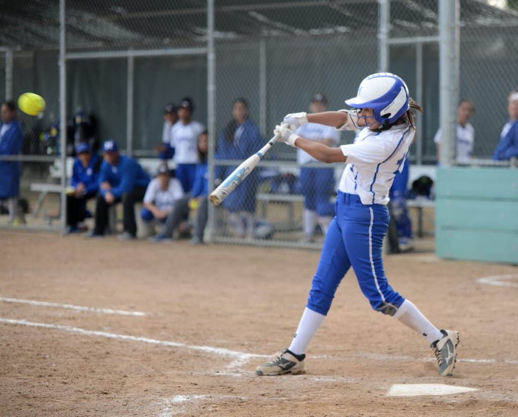 Softball player swinging at a pitch during a game.