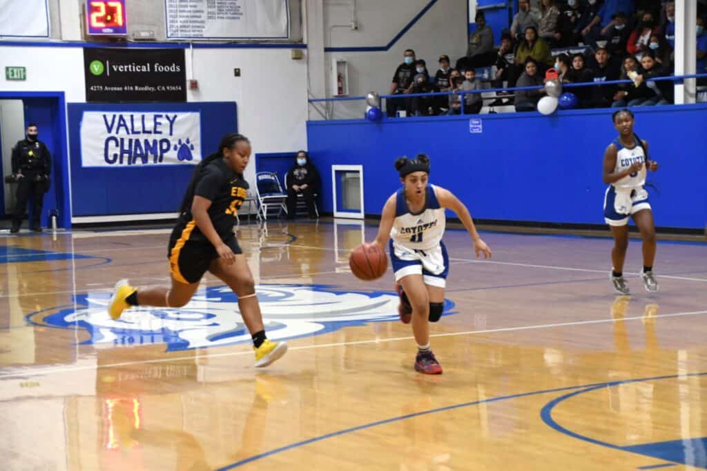 Young female basketball players competing in a high school game.