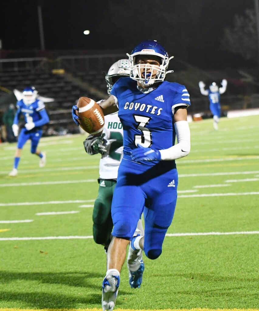Madera High School football player running with the ball during a game.