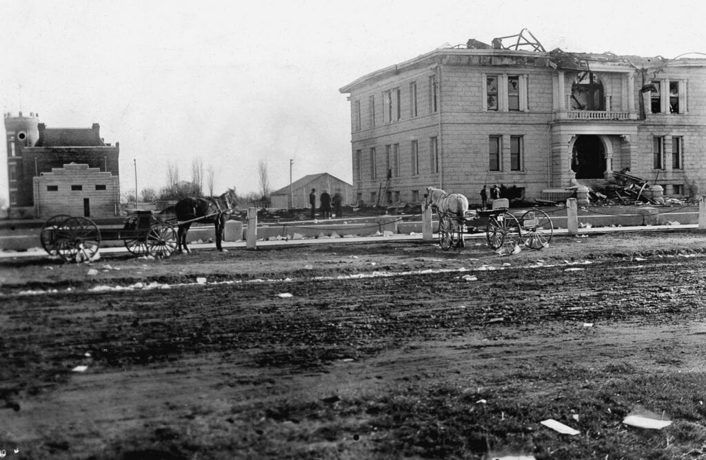 Early 20th-century photo of damaged building and horses in Madera.