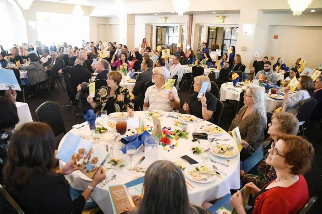 Community members at a Madera Tribune event holding up books or programs.