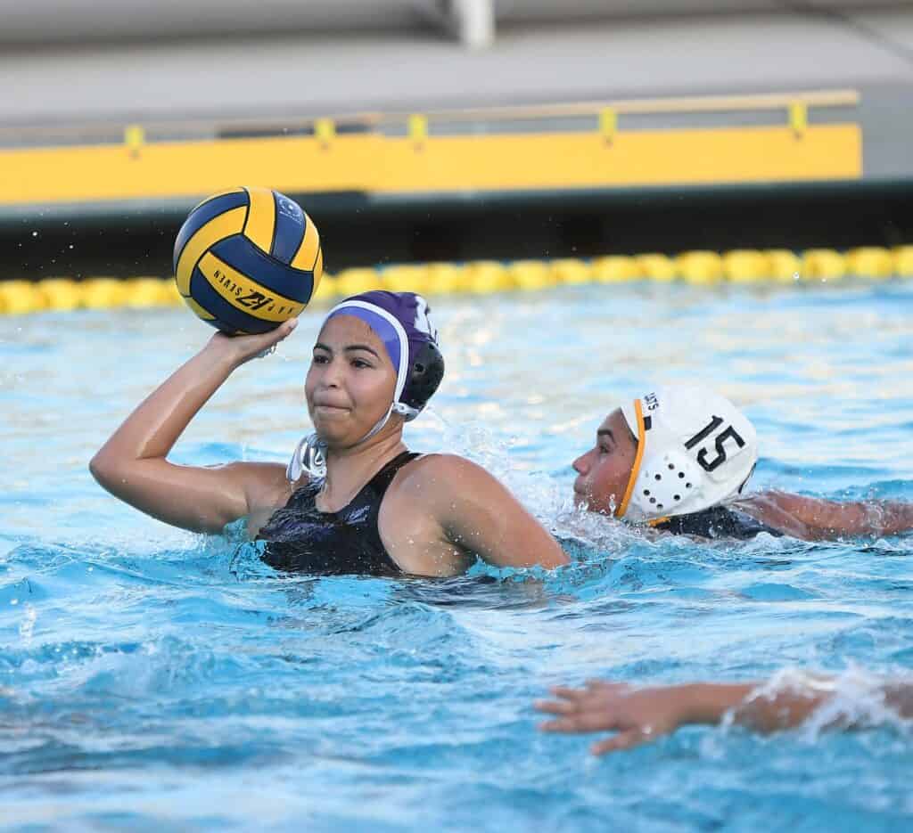 Water polo player holding ball during match.