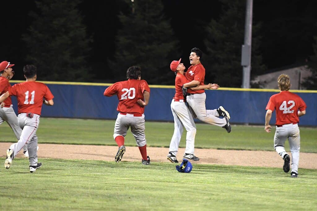 Youth baseball players celebrating on the field after a game.