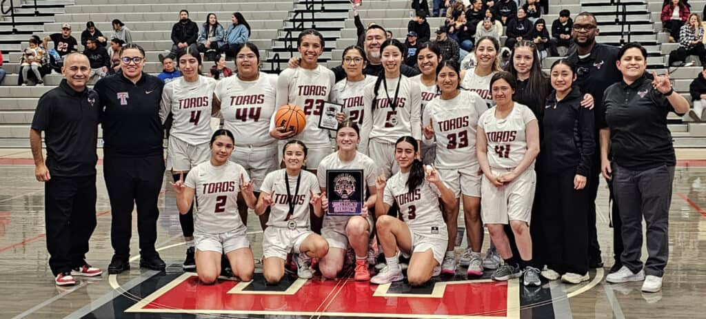 Photo of The Matilda Torres Toros girls basketball team celebrates at center court after a 46-24 victory over the Mendota Aztecs to win the fifth annual Cen-Cal Holiday Invitational at Torres. 
