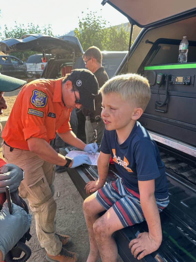 Emergency responder assisting young boy at community event.