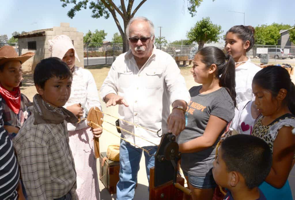 Instructor teaching children how to use woodworking tools outdoors in Madera.