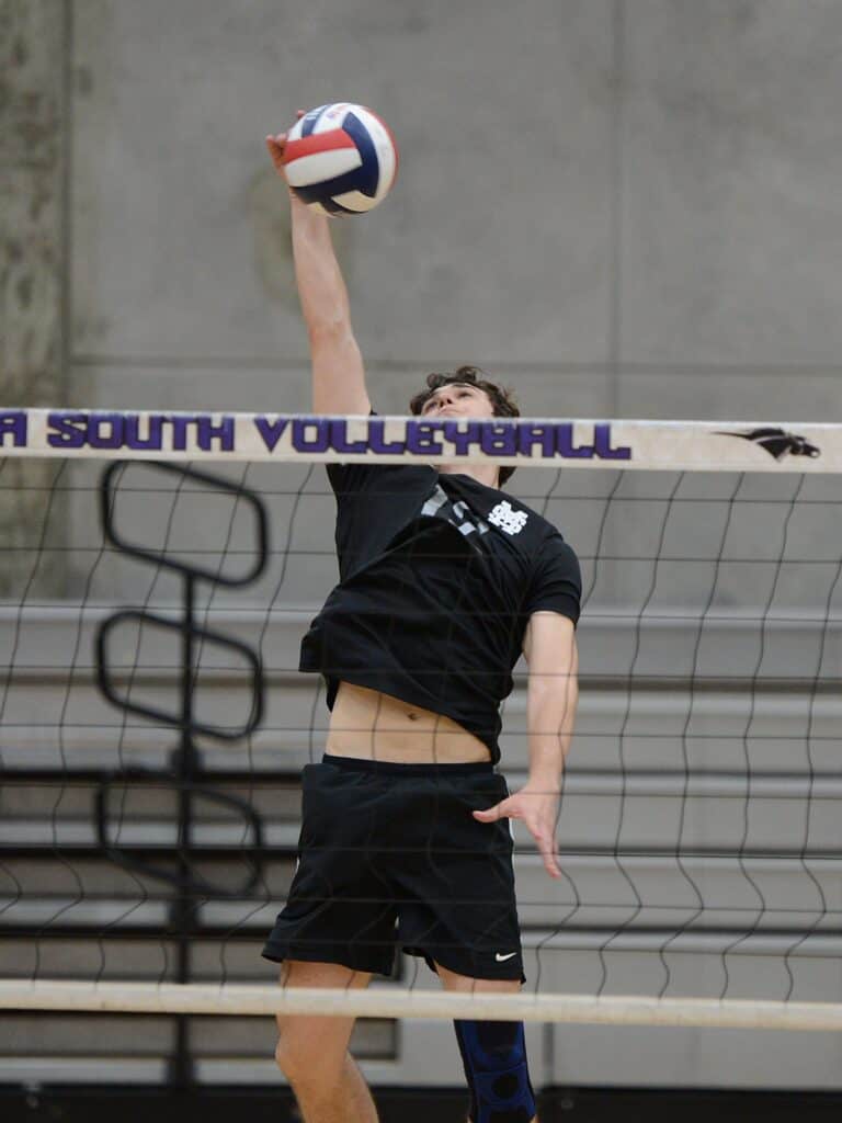 Volleyball player jumping to spike during match at Madera gym.