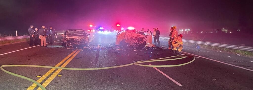 Car accident on highway at night with emergency responders and damaged vehicles.