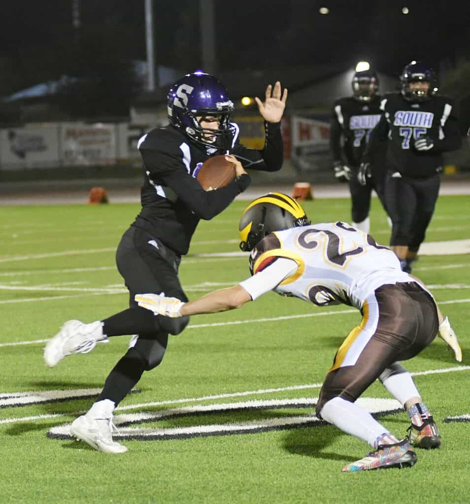 Madera football player evades tackle during night game.