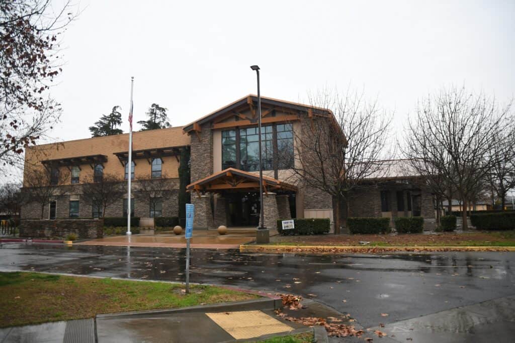 Madera Tribune office building on a rainy day with trees and parking lot.