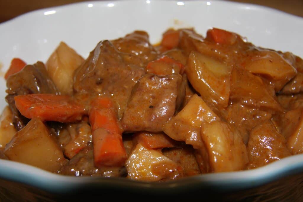 Beef stew with carrots, potatoes, and gravy in a white bowl.