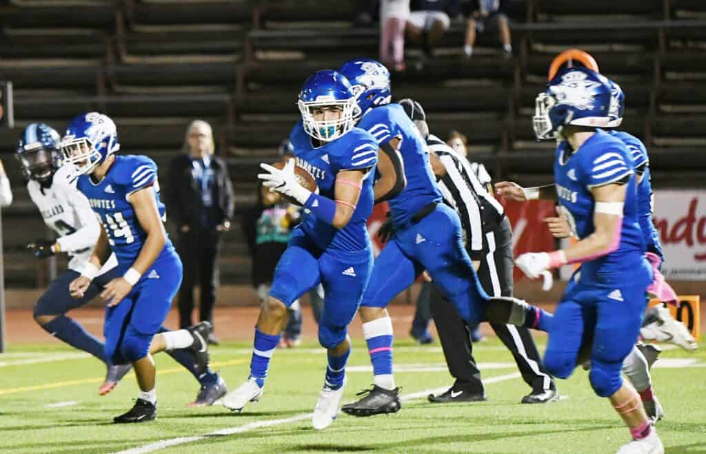 Madera High football players in blue uniforms during a game.