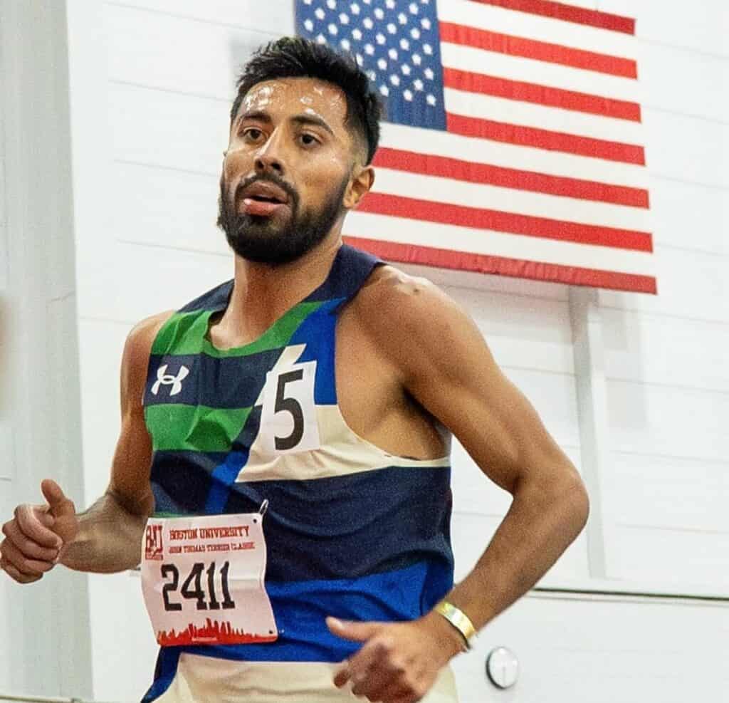 Athlete running in a race with American flag background.