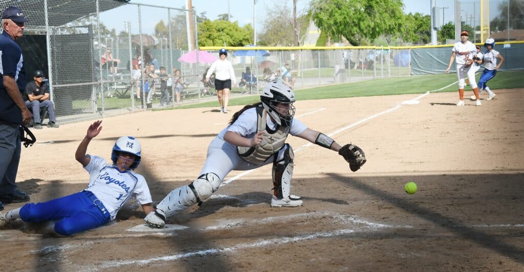 Youth baseball player sliding into home plate during game.