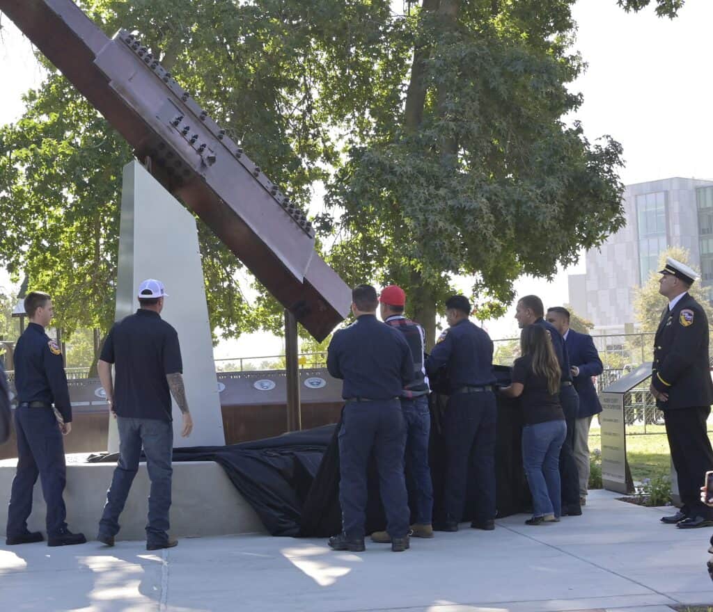 Madera community gathers around a memorial with a large sculpture and a group of people paying tribu.