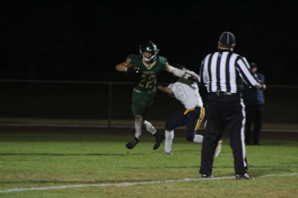Madera high school football player running with the ball during a night game.