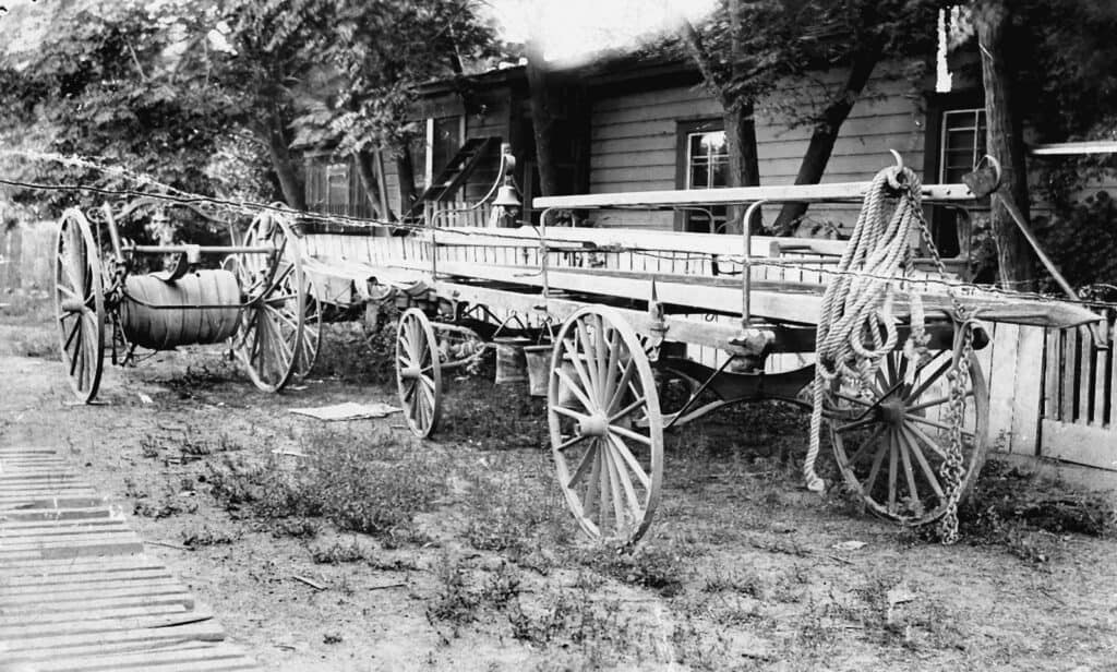 Vintage wooden wagon with large wheels and ropes in a rural outdoor scene.