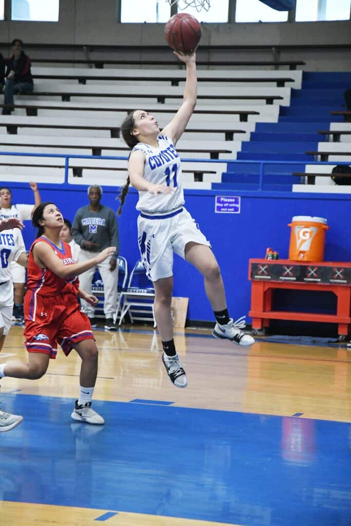 Young female basketball player jumping for a shot during a game.