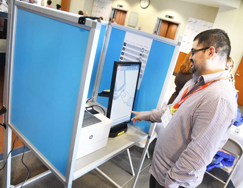 Man voting using electronic voting machine at polling station.