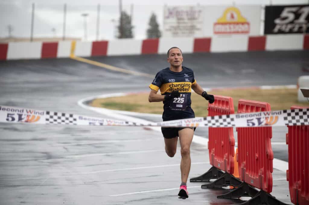 Runner crossing finish line at Madera race event.