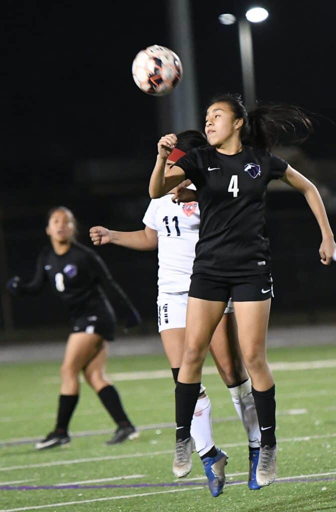 Soccer player jumping to head the ball during a night match.