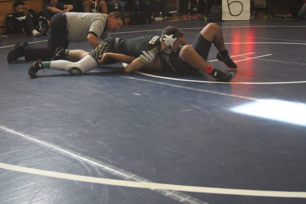 Wrestlers competing in a match at the Madera wrestling tournament on a blue mat.