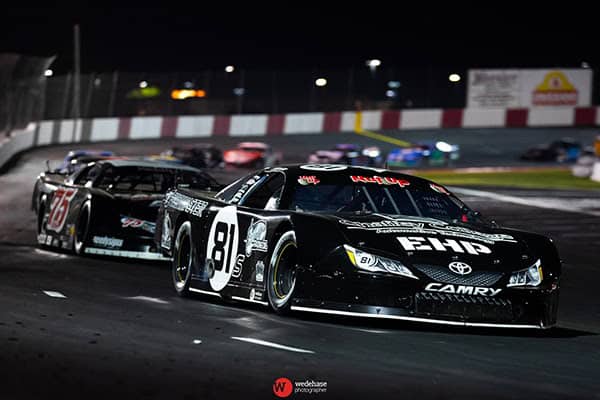 Race car speeding on track during night race event.