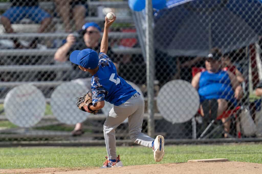 Young baseball player pitching during a youth game at Madera field.