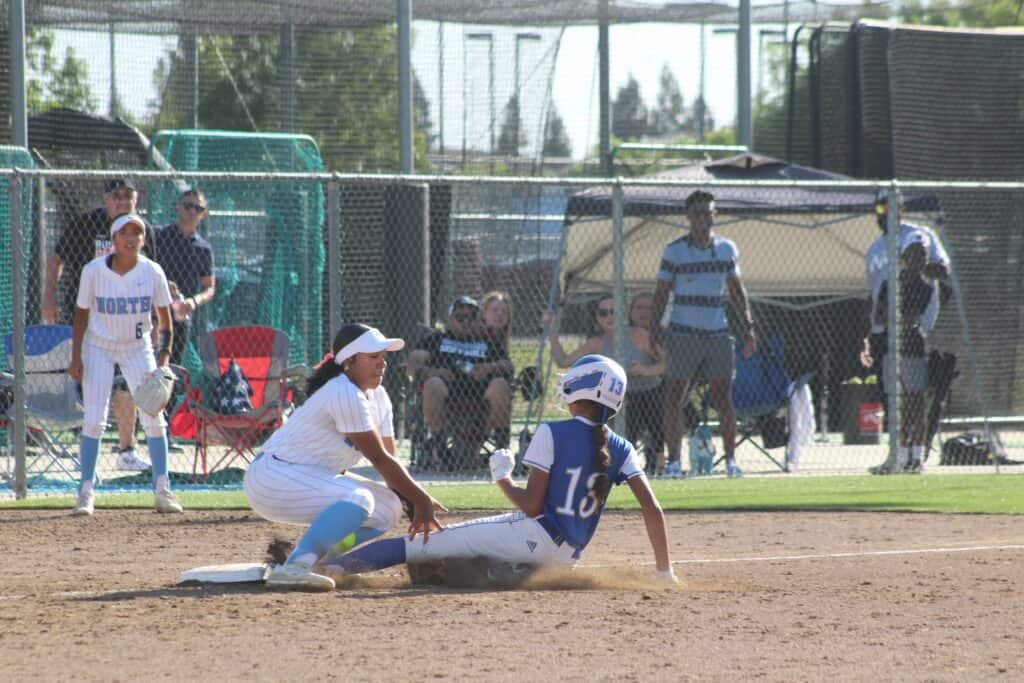 Young baseball player sliding into home plate during a game.