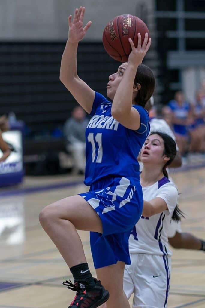 Young female basketball player jumping for a shot during a game.