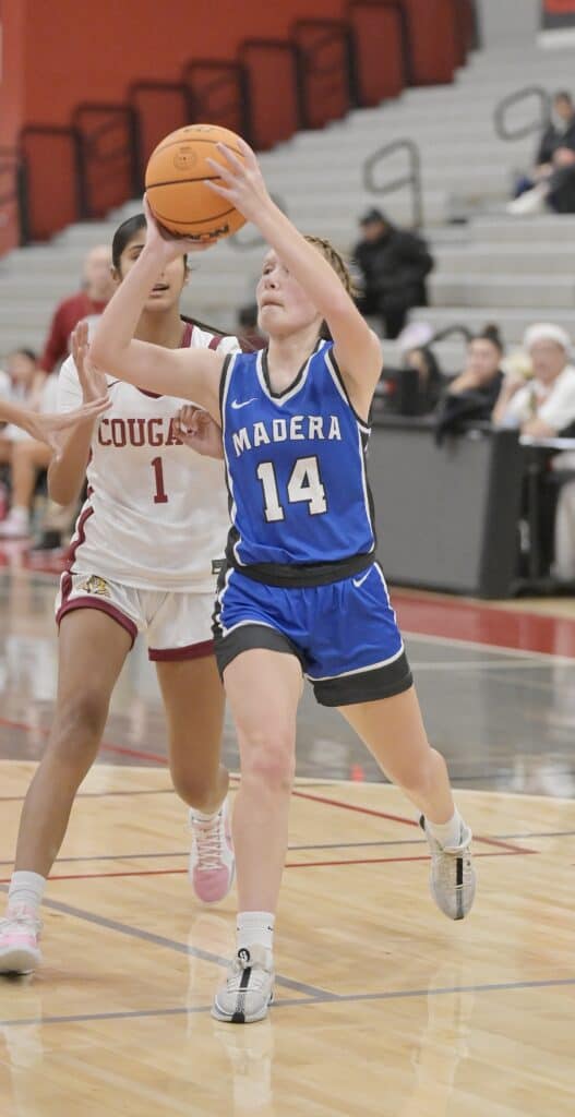 Young female basketball player in blue jersey dribbling during game.