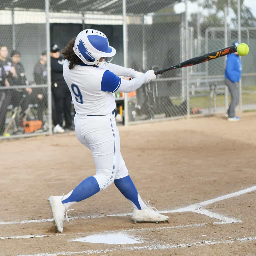 Female softball player swinging bat during game at Madera field.