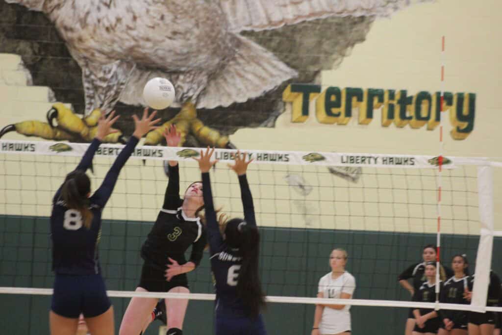 Volleyball players jumping to hit the ball during a match at Madera.