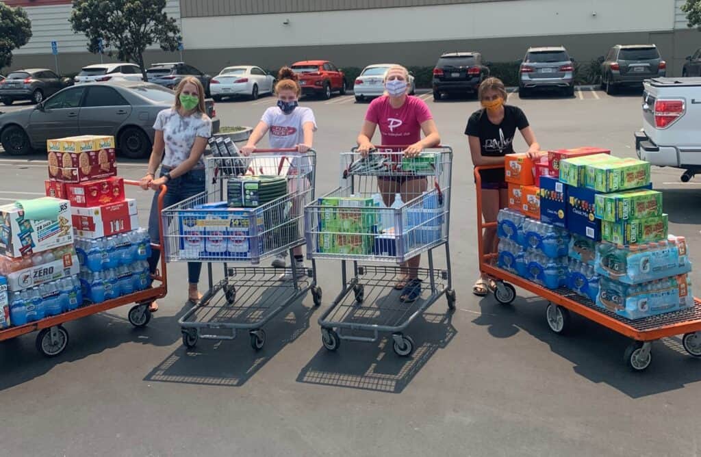 People wearing masks with shopping carts full of supplies.
