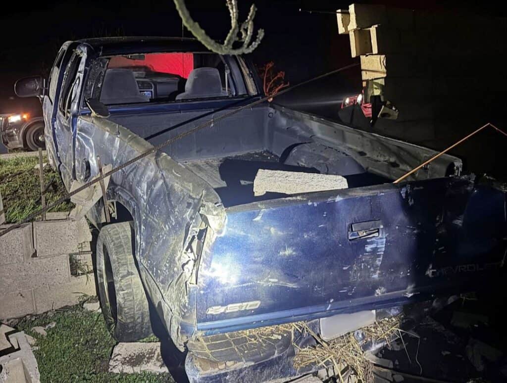 Damaged blue Chevrolet pickup truck with visible dents and scratches from a collision.