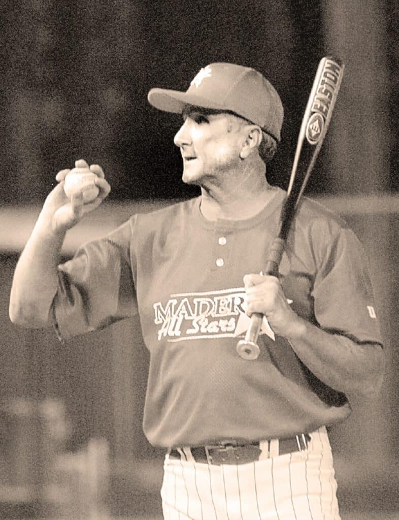 Madera baseball player holding a bat and celebrating on the field.